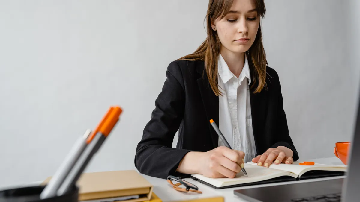 AI content writing workflow for ecommerce product pages — Woman Sitting by Desk Writing in Notebook