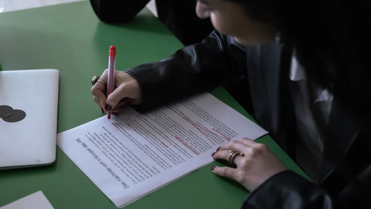 Person marking up a printed document with a pen