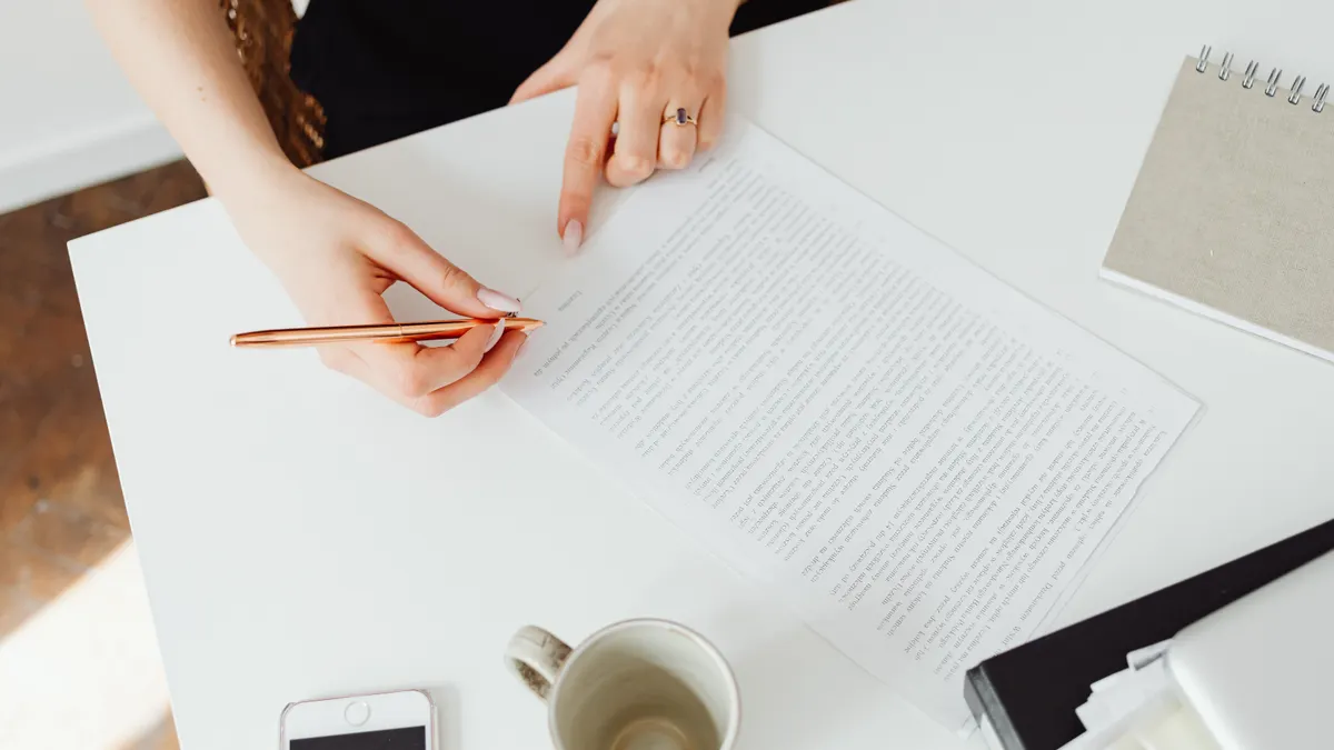 Person annotating a printed document at a white desk