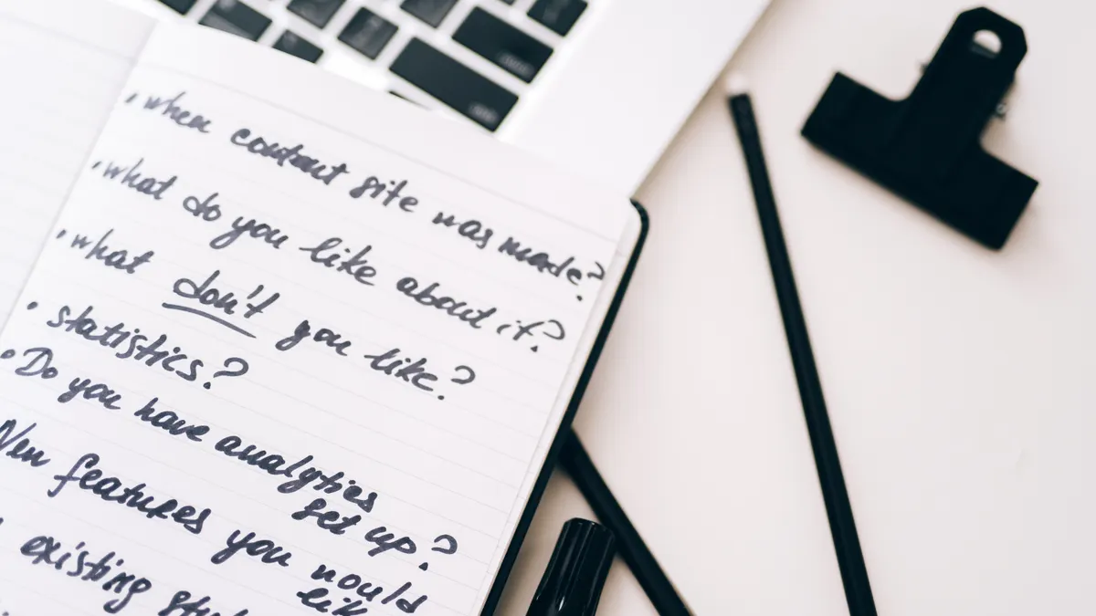 Notebook with brief questions beside a laptop clip